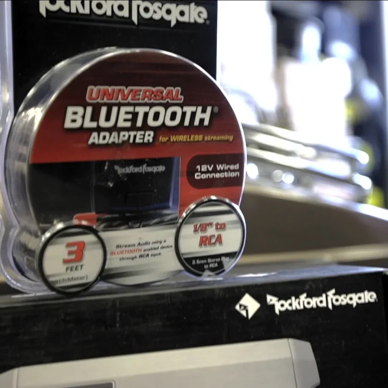 Rockford Fosgate Universal Bluetooth Adapter product on display, featuring packaging that highlights “Wireless streaming,” “12V Wired Connection,” and compatibility via a 3-foot 1/8" to RCA cable.