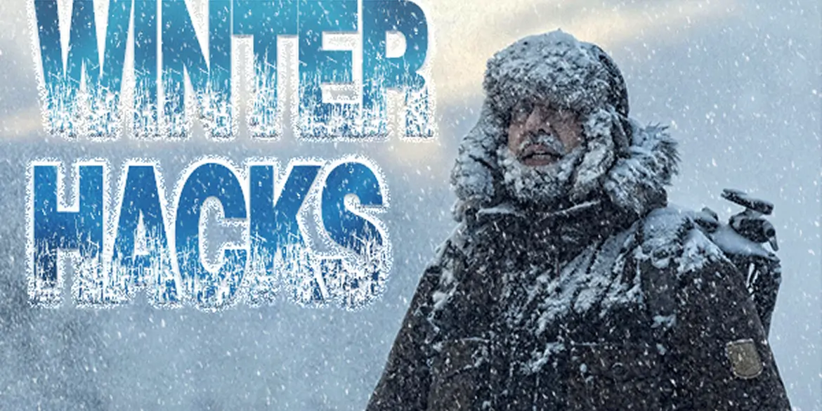 Man bundled in a heavy, fur-lined winter coat and hat, covered in snow during a blizzard, stands next to large frosty text reading “WINTER HACKS.”