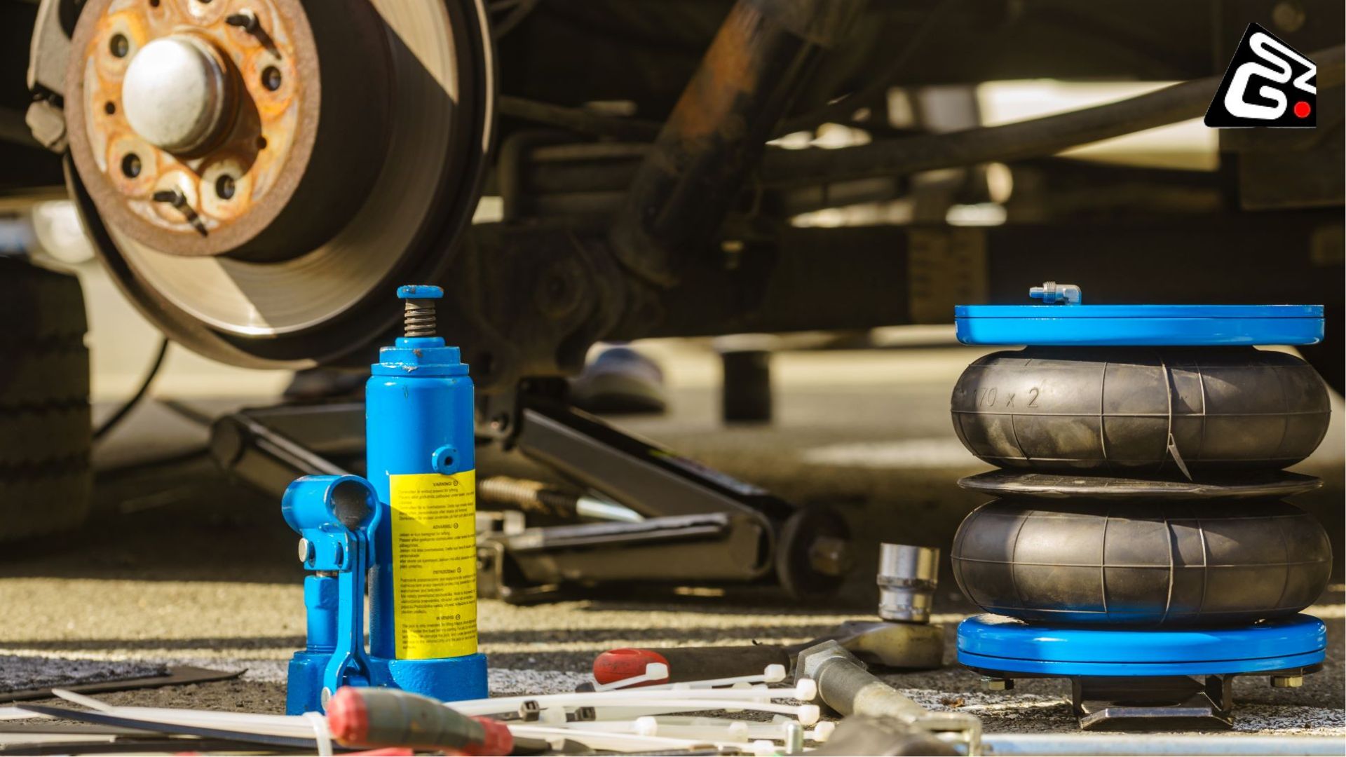 A close-up of tools and suspension parts, including air bags, used in the lift kit installation process on a vehicle.
