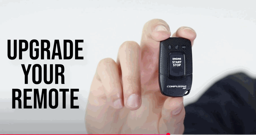 A person holding a compact Compustar key fob with a prominent engine start/stop button and the text “Upgrade Your Remote”.