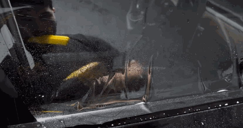 Close-up of a tint film being aligned and tucked into place along the bottom edge of a car window.