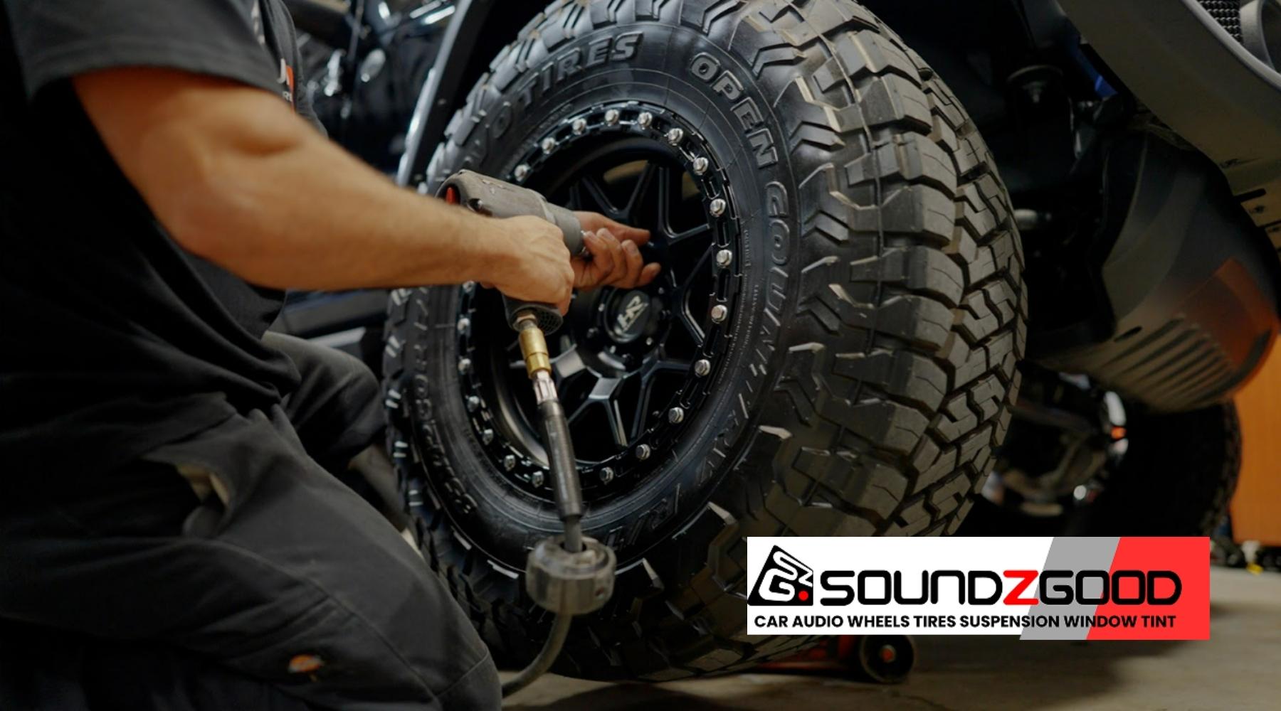 Technician installing custom off-road wheel and tire at Soundz Good Garage in Oxnard, CA