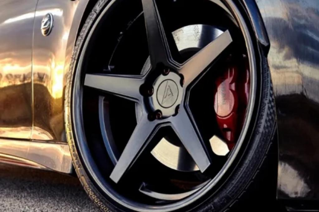 Close-up of a matte black five-spoke custom wheel on a sports car with red brake calipers