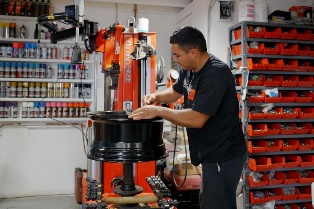 Technician preparing a black alloy wheel for mounting in a professional tire shop