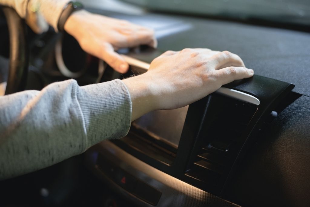 Technician installing a car stereo head unit during professional car audio installation in vehicle dashboard