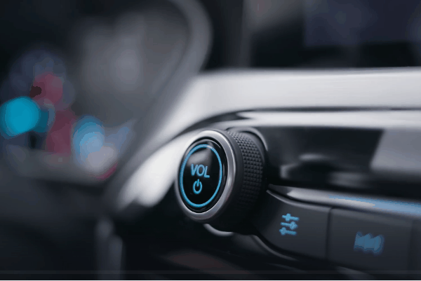 Driver adjusting a modern car infotainment control knob on a touchscreen audio system for enhanced in-car entertainment.