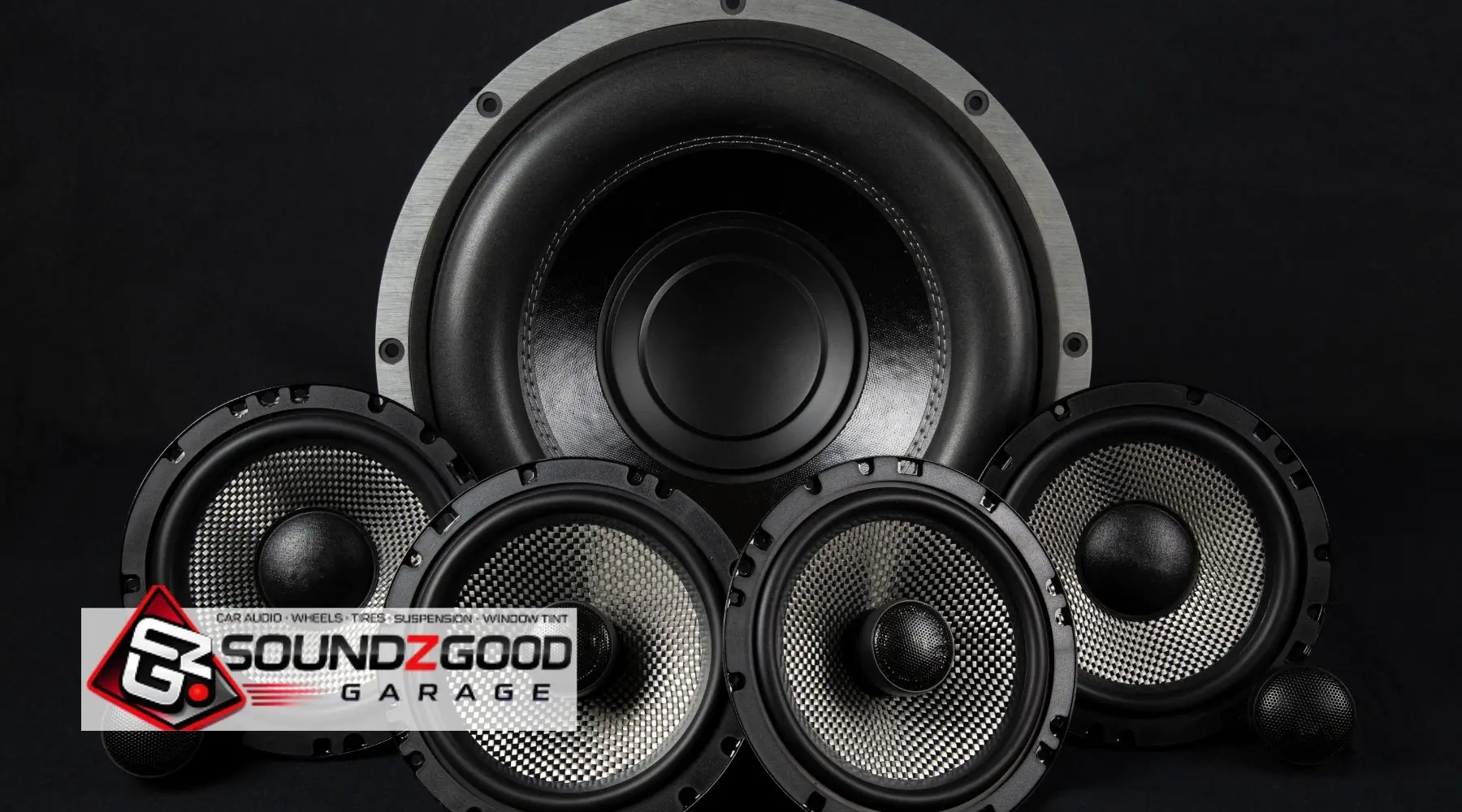 Car audio speakers and subwoofer display with Soundz Good Garage logo on a black background