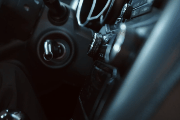 Close-up view of a car interior dashboard with audio controls, vents, and steering wheel in low light.