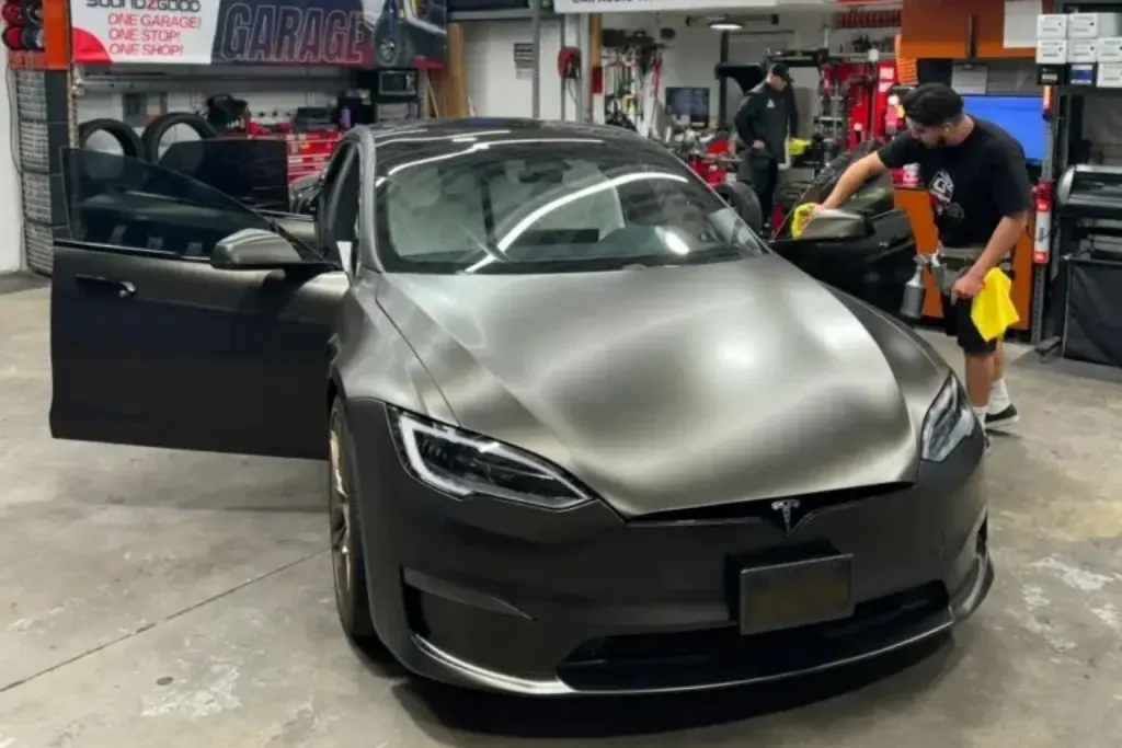 Technician cleaning and preparing a matte black Tesla for professional ceramic window tint installation inside Soundz Good Garage.