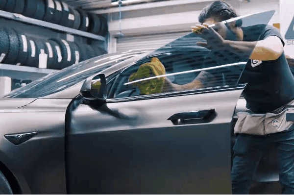 Technician installing window film on a car window inside Soundz Good Garage
