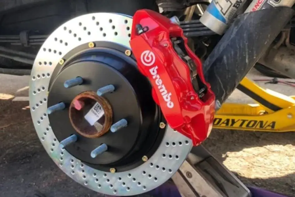 Close-up of upgraded brake rotor and red Brembo caliper during vehicle service.