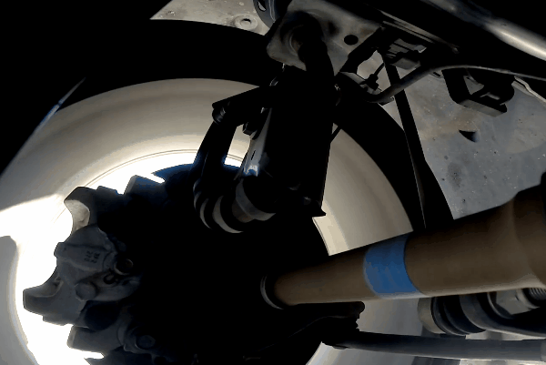 Undercarriage view of vehicle wheel, axle, and suspension components during movement