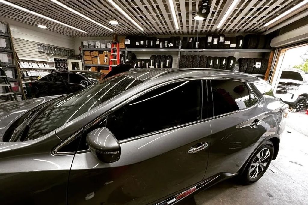Gray SUV with professionally tinted side windows inside an automotive customization shop.