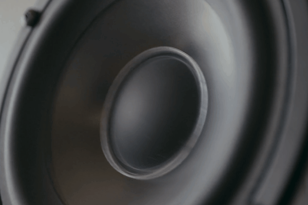 Close-up animation of a car speaker cone vibrating while playing audio.