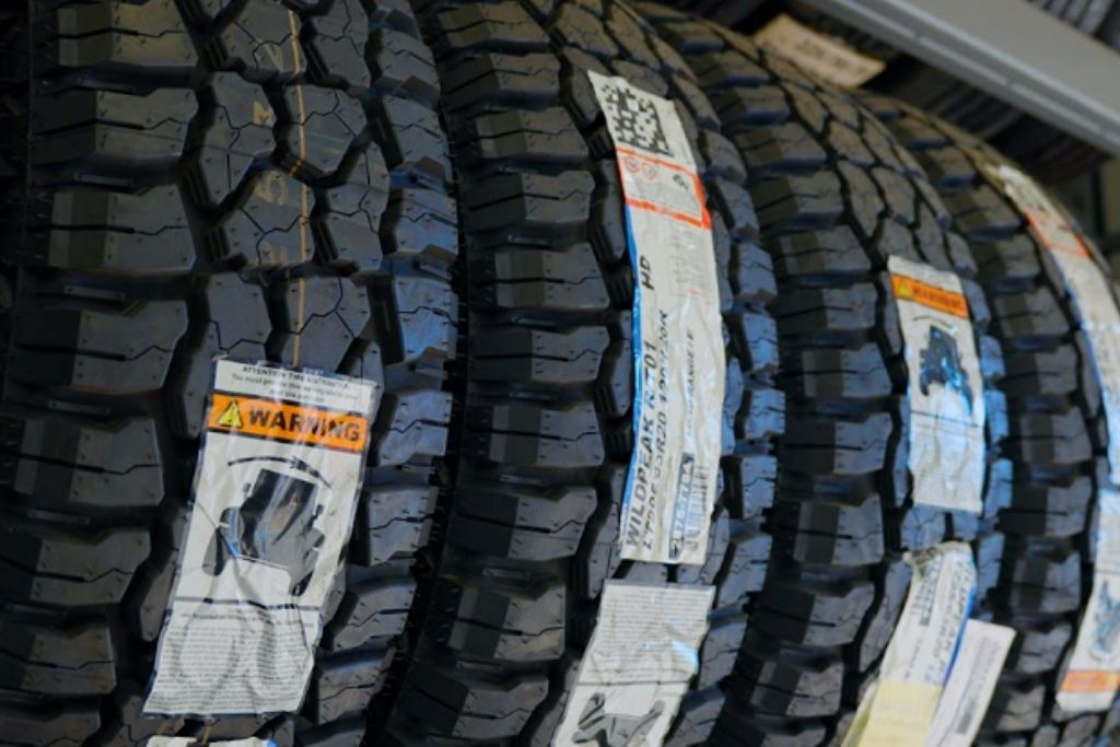 Rows of rugged all-terrain tires with deep tread patterns displayed in a tire shop.