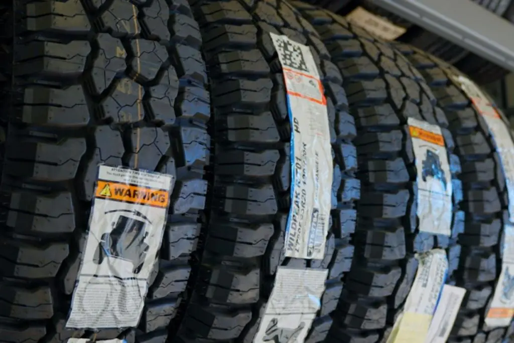 Rows of rugged all-terrain tires with deep tread patterns displayed in a tire shop.