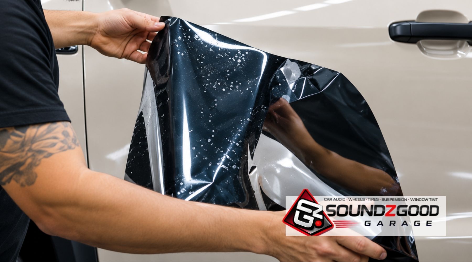 Technician applying automotive window tint film to a vehicle at Soundz Good Garage.