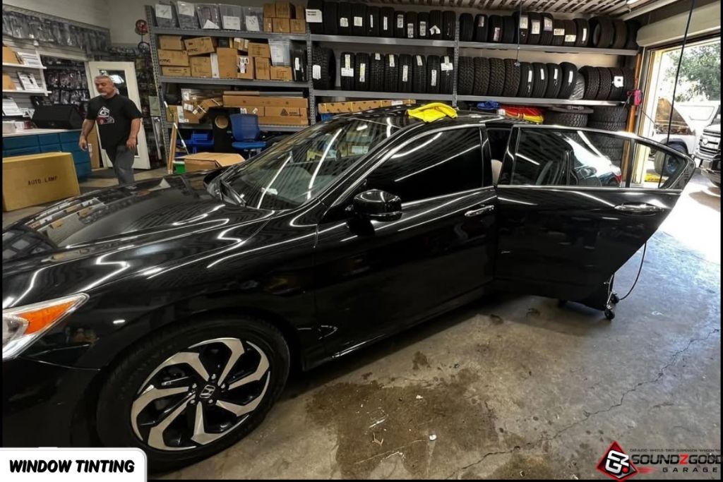 Black sedan with professionally tinted windows inside Soundz Good Garage.