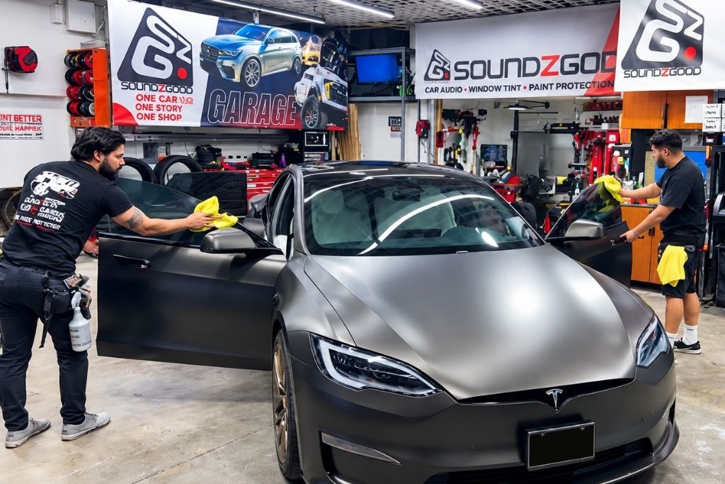 Soundz Good Garage technicians cleaning and preparing a Tesla for professional window tint installation.