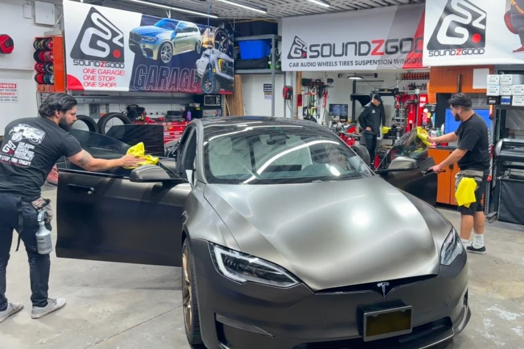 Soundz Good Garage technicians working on a Tesla during professional automotive window tint service.