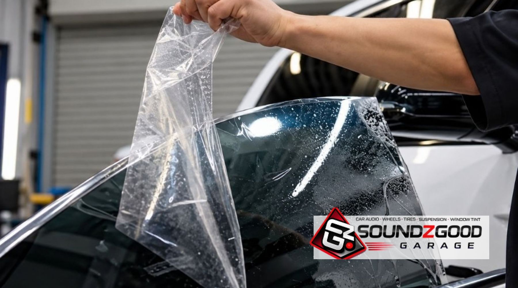 Professional removing old car window tint from a side window before installing replacement automotive window film.